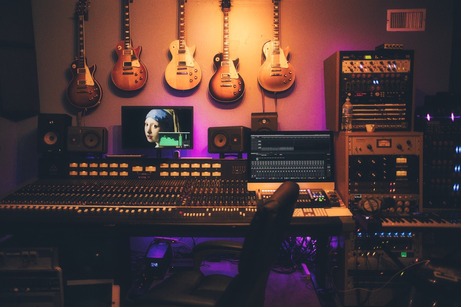 Studioaufnahme eines Tonstudios auf Funky Shamans Webseite. Das Bild zeigt eine Ansicht von einem Multimedia Studio mit Klavier, Klavierhocker, 5 Gitarren an der Wand hängend, großem Mischpult, Kopfhörer, Abhörmonitore, Stereoanlage und einer Menge Studioequipment.
